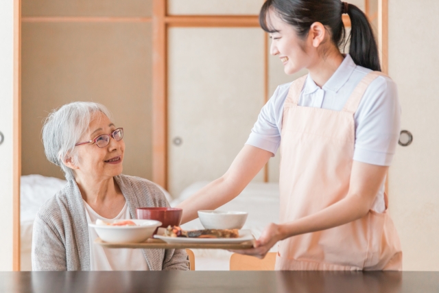 食事をする高齢者女性とスタッフ